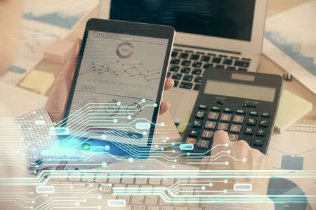 Double exposure of man's hand holding and using a digital device and data theme hologram drawing....