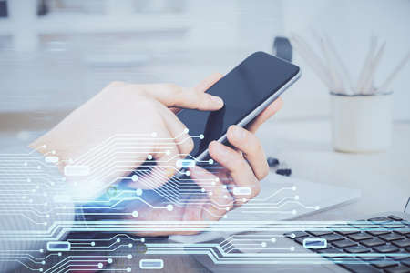 Double exposure of man's hand holding and using a digital device and data theme hologram drawing....