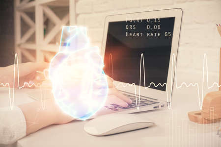 Double exposure of woman hands typing on computer and heart hologram drawing. Education concept.の写真素材