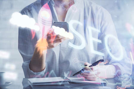 Double exposure of SEO sketch hologram and woman holding and using a mobile device.の写真素材