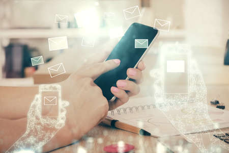 Double exposure of man's hands holding and using a digital device and envelop hologram drawing. E-mail concept.の写真素材