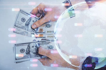Double exposure of world map drawing hologram and us dollars bills and man hands.