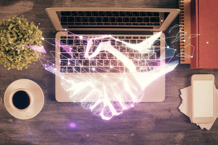 Handshake drawing over computer on the desktop background. Top view. Double exposure. Partnership concept.の写真素材