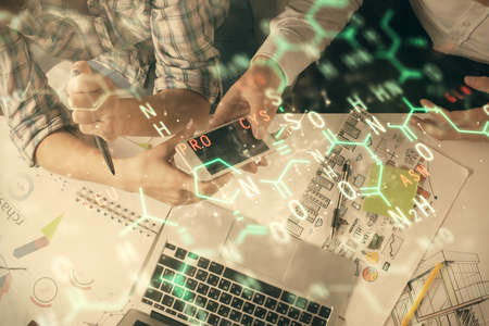 Double exposure of formulas hologram drawing and man and woman working together holding and using a mobile device. Education conceptの写真素材