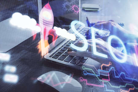 Double exposure of woman hands working on computer and seo hologram drawing. internet search...