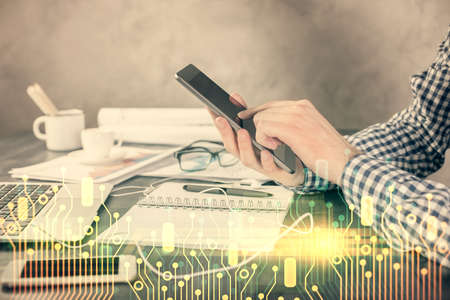 Double exposure of man's hand holding and using a digital device and data theme hologram drawing....