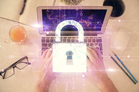Multi exposure of man's hands typing over computer keyboard and lock hologram drawing. Top view....