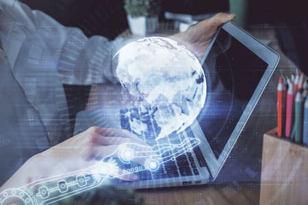 Double exposure of woman hands working on computer and world map hologram drawing. International...