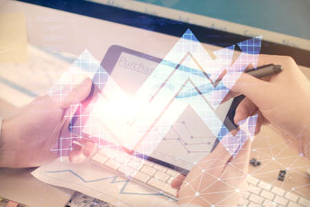 Double exposure of man's hands holding and using a digital device and arrows hologram drawing....