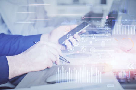 Double exposure of man's hand holding and using a digital device and data theme hologram drawing....
