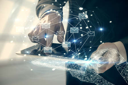 Double exposure of man's hands holding and using a digital device and envelop hologram drawing....