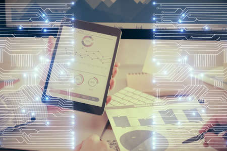 Double exposure of man's hands holding and using a digital device and tech theme hologram drawing....