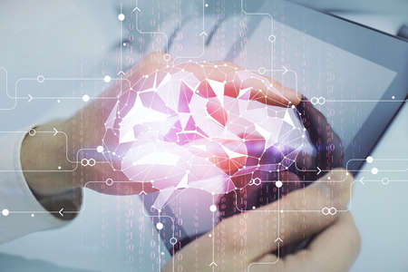 Double exposure of man's hand holding and using a digital device and brain hologram drawing. Data...