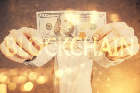 Multi exposure of blockchain theme drawing hologram and USA dollars bills and man hands. Business concept.の写真素材