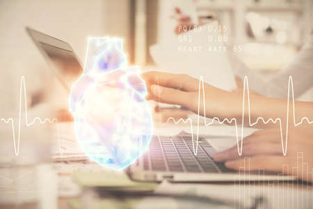 Double exposure of woman hands typing on computer and heart hologram drawing. Education concept.