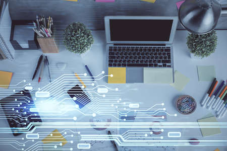 Double exposure of data drawing hologram over topview of study desk background with computer....
