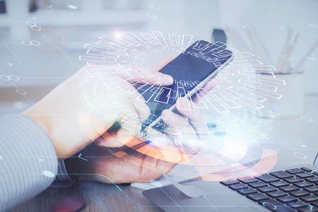 Double exposure of man's hand holding and using a digital device and data theme hologram drawing. Technology concept.の写真素材