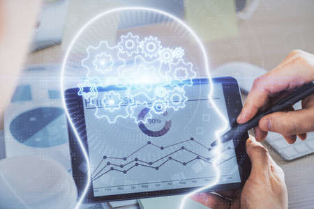 Double exposure of man's hand holding and using a digital device and brain hologram drawing. Data...