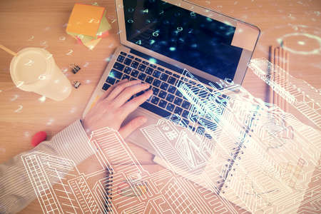 Double exposure of man's hands typing over computer keyboard and buildings drawing. Top view. smart...
