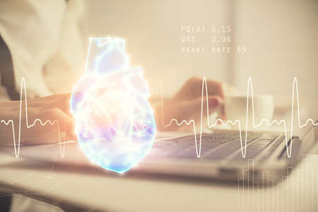 Double exposure of woman hands typing on computer and heart hologram drawing. Education concept.の写真素材