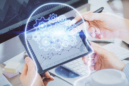 Double exposure of man's hand holding and using a digital device and brain hologram drawing. Data...
