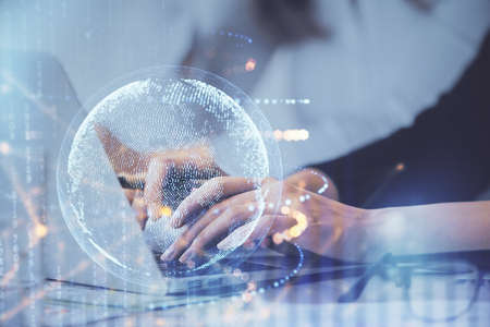 Double exposure of woman hands working on computer and world map hologram drawing. International...