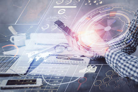 Double exposure of man's hand holding and using a digital device and data theme hologram drawing....