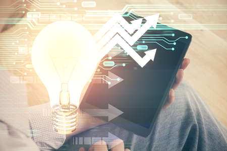 Double exposure of man's hands holding and using a digital device and bulb hologram drawing. idea...