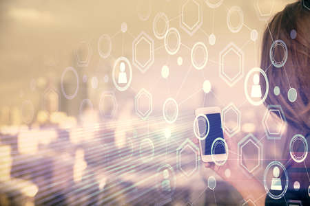 Double exposure of social network sketch hologram and woman holding and using a mobile device.