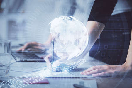 Double exposure of woman hands working on computer and world map hologram drawing. International...