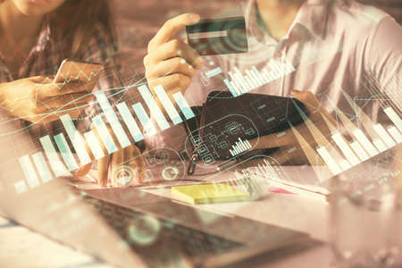 Double exposure of man and woman on-line shopping holding a credit card and forex graph hologram drawing. Stock market E-commerce pay on-line concept.の写真素材