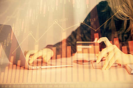 Double exposure of woman on-line shopping holding a credit card and financial graph drawing. Stock market E-commerce concept.の写真素材