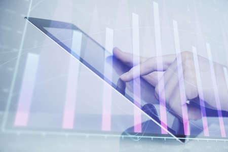 Multi exposure of man's hands holding and using a digital phone and forex graph drawing. Financial...