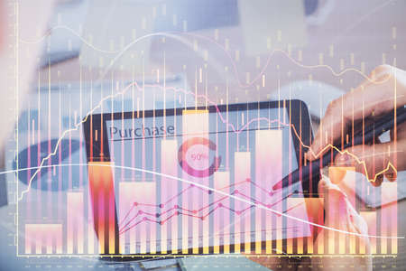 Double exposure of man's hands holding and using a phone and financial chart drawing. Market...