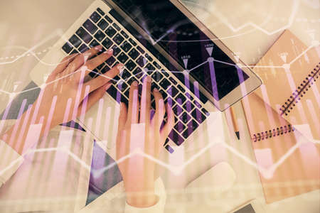 Double exposure of woman hands working on computer and forex graph hologram drawing. Top View....