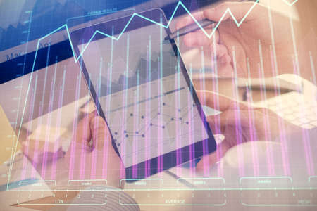 Double exposure of man's hands holding and using a phone and financial chart drawing. Market...