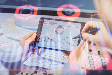 Double exposure of man's hands holding and using a phone and financial chart drawing. Market...