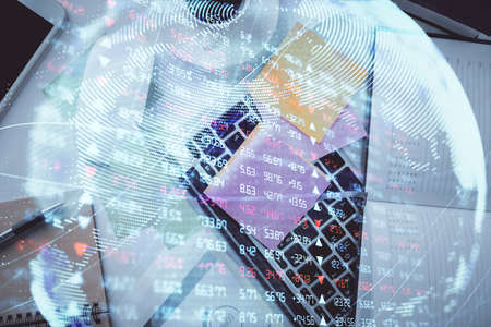 Business theme hologram drawings over computer on the desktop background. Top view. Multi exposure....