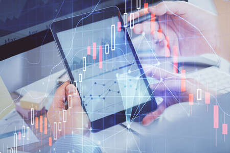 Double exposure of man's hands holding and using a phone and financial chart drawing. Market analysis concept.の写真素材