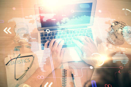 Multi exposure of man's hands typing over computer keyboard and world map hologram drawing. Top...