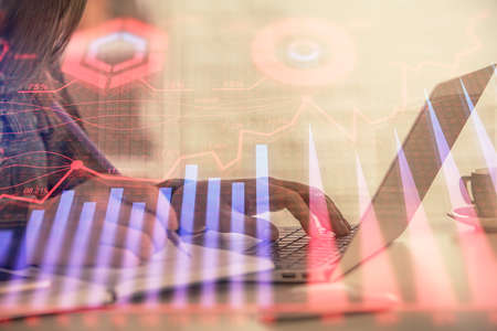 Double exposure of businesswoman hands typing on computer and forex graph hologram drawing....