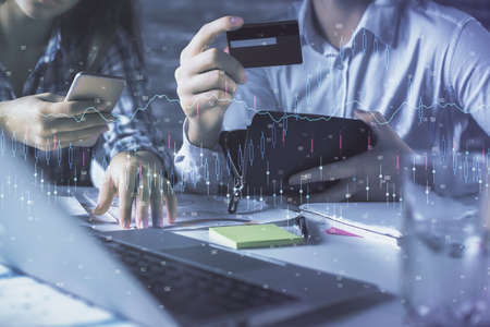 Double exposure of man and woman on-line shopping holding a credit card and forex graph hologram...
