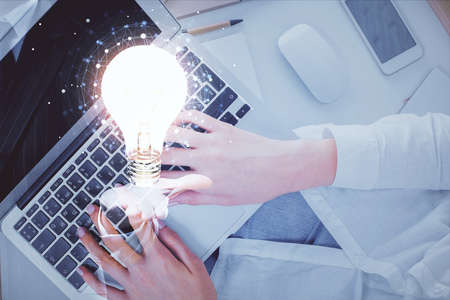 Double exposure of woman hands working on computer and light bulb hologram drawing. Top View. Idea concept.の写真素材