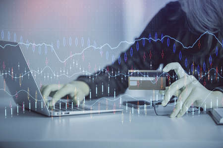 Double exposure of woman on-line shopping holding a credit card and financial graph drawing. Stock...
