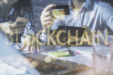 Double exposure of man and woman on-line shopping holding a credit card and crypto theme hologram...