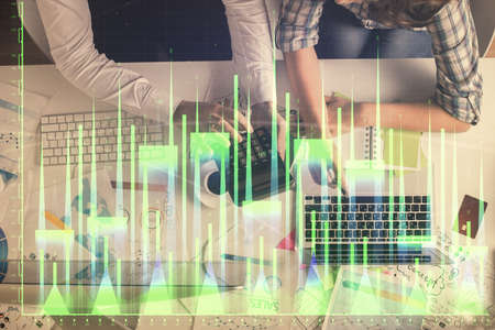 Double exposure of man and woman working together and financial graph hologram drawing. market...