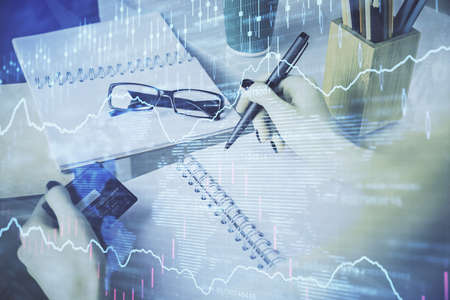 Multi exposure of woman on-line shopping holding a credit card and financial graph drawing. Stock...