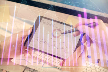 Double exposure of man's hands holding and using a phone and financial chart drawing. Market...