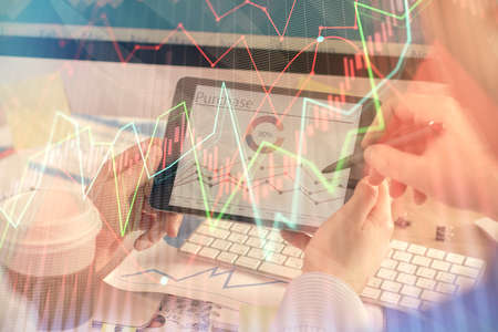 Double exposure of man's hands holding and using a phone and financial chart drawing. Market...