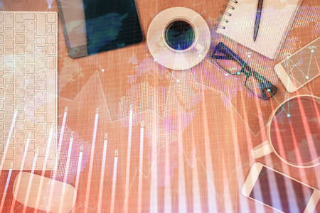 Double exposure of financial chart hologram over desktop with phone. Top view. Mobile trade platform...